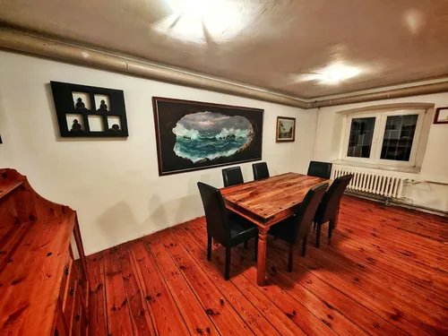 Speisezimmer mit massivem Holztisch, Dielenboden und Gemälden